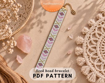 May include: A long, narrow seed bead bracelet featuring a repeating geometric pattern in shades of white, light pink, lavender, and gold. The bracelet includes a gold-toned metal clasp and an adjustable chain extension with a small circular charm.