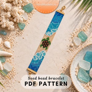 May include: A rectangular seed bead bracelet featuring a central sea turtle motif on a sandy beige background, flanked by blue and white wave patterns. The bracelet has gold-toned metal end caps and a lobster clasp closure at one end.