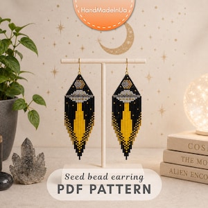 Puede incluir: Un par de pendientes largos de cuentas en forma de diamante con fondo negro, un diseño de OVNI gris y un haz de luz amarillo que se extiende hacia abajo. Se exhiben en un soporte blanco en forma de T con el texto Seed bead earring PDF PATTERN.