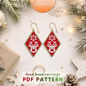 May include: A pair of diamond-shaped seed bead earrings featuring a red background with a white reindeer and snowflake pattern. The earrings have gold-toned metal hooks. The text "Seed bead earrings PDF PATTERN" is printed at the bottom of the image.