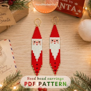 May include: A pair of long, pointed seed bead earrings featuring a Santa Claus design. The earrings are crafted with red, white, and black beads, depicting a red hat, a white beard, and a red coat with black buttons. Gold-tone ear wires are attached.