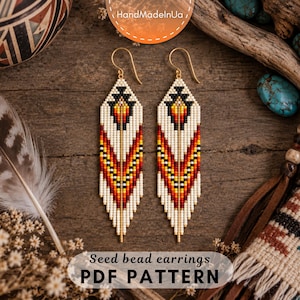 May include: A pair of long, diamond-shaped seed bead earrings featuring a geometric pattern in white, black, yellow, orange, and red. The earrings hang from gold-toned metal hooks and include a fringe of beads at the bottom point.