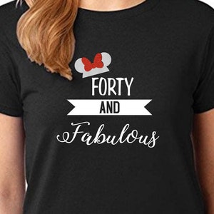 Pode incluir: Camiseta preta com um gr&aacute;fico branco que diz "Forty and Fabulous" com um design de orelha de Mickey Mouse vermelho e branco sobre o texto.