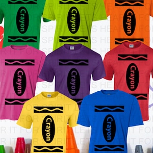 May include: A collection of eight short-sleeve t-shirts in green, lime, orange, pink, purple, red, yellow, and blue. Each shirt features a black graphic design resembling a crayon wrapper with the word Crayon printed in the center.