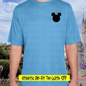 May include: Light blue athletic tee shirt with a black Mickey Mouse head graphic. The shirt has the text "Athletic Dri-fit Tee With SPF" in a yellow rectangle. The shirt is made of a moisture-wicking material.