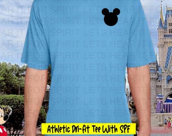 Peut inclure: Un t-shirt de sport bleu clair à manches courtes en tissu dri-fit, orné d'une silhouette noire de tête de Mickey Mouse sur la poitrine gauche. Le t-shirt comporte une étiquette rectangulaire jaune avec le texte Athletic Dri-fit Tee With SPF.
