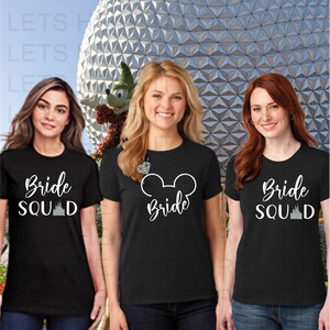 May include: Three black t-shirts with white text and graphics. The shirts say "Bride Squad" with a castle graphic, "Bride" with a Mickey Mouse ear graphic, and "Bride Squad" with a castle graphic.