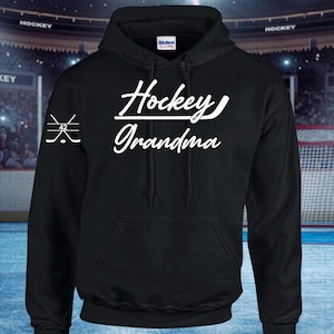May include: Black hooded sweatshirt with white text that reads "Hockey Grandma" and a hockey stick graphic. The left sleeve has a graphic of two crossed hockey sticks.