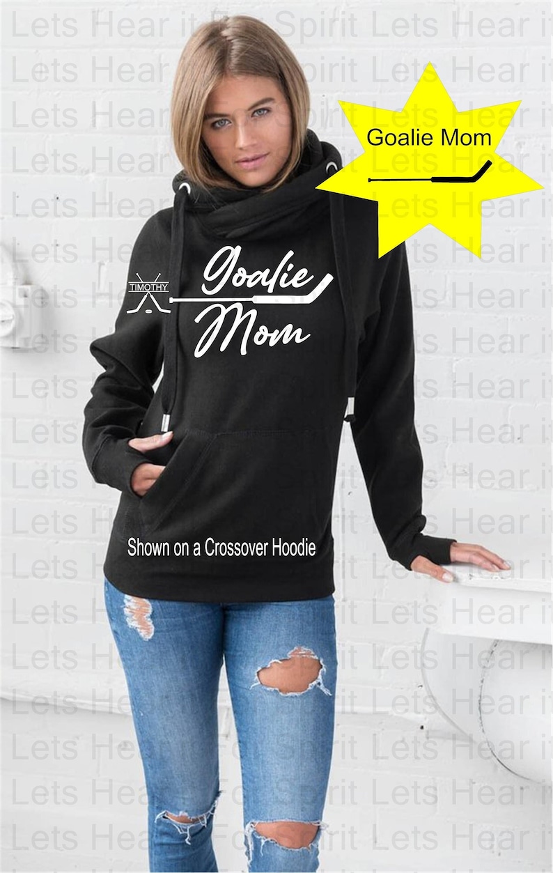 K&ouml;nnte beinhalten: Schwarzer Crossover-Hoodie mit einer wei&szlig;en Grafik, auf der "Goalie Mom" mit einem Hockeyschl&auml;ger steht. Der Hoodie hat an jedem &Auml;rmel ein Daumenloch.