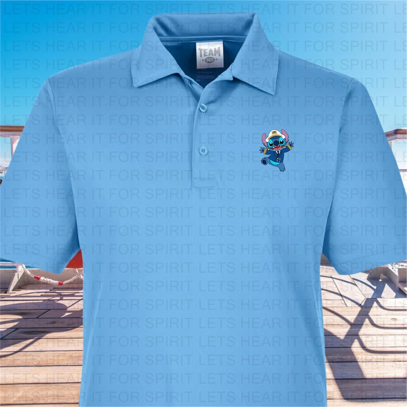 Puede incluir: Una camisa polo azul claro con un patr&oacute;n repetido del texto "Lets Hear It For Spirit". La camisa presenta una peque&ntilde;a imagen bordada de un personaje azul con un sombrero de capit&aacute;n y una camisa blanca, sosteniendo un salvavidas azul.