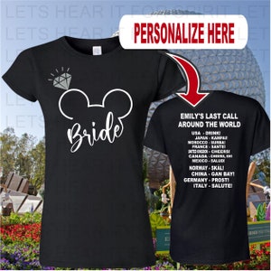 May include: Black t-shirt with a white Mickey Mouse ears design and the word "Bride" written in white script. The back of the shirt has white text that says "Emily's Last Call Around the World" and lists different countries with their respective cheers.