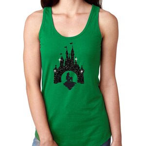 Puede incluir: Una camiseta sin mangas verde con un dise&ntilde;o de silueta negra de un castillo, una sirena y estrellas. El dise&ntilde;o est&aacute; centrado en la parte delantera. La camiseta sin mangas es sin mangas con cuello redondo.