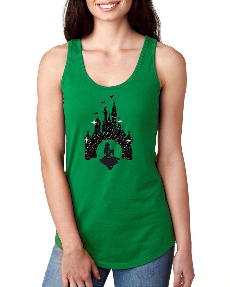 Puede incluir: Una camiseta sin mangas verde con un dise&ntilde;o de silueta negra de un castillo, una sirena y estrellas. El dise&ntilde;o est&aacute; centrado en la parte delantera. La camiseta sin mangas es sin mangas con cuello redondo.