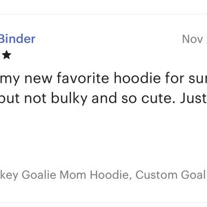 Puede incluir: Una rese&ntilde;a de un cliente para una sudadera gris con el texto "Hockey Goalie Mom Hoodie, Custom Goalie Mo..." La rese&ntilde;a es de cinco estrellas y dice "&iexcl;Esta es mi nueva sudadera favorita! C&aacute;lida pero no voluminosa y tan linda. &iexcl;Me encanta!"