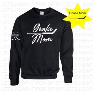 K&ouml;nnte beinhalten: Schwarzer Pullover mit wei&szlig;em Text, der "Goalie Mom" lautet, und einer Grafik eines Hockeyschl&auml;gers. Der linke &Auml;rmel hat eine kleine wei&szlig;e Grafik von zwei gekreuzten Hockeyschl&auml;gern mit dem Wort "Patrick" dar&uuml;ber.