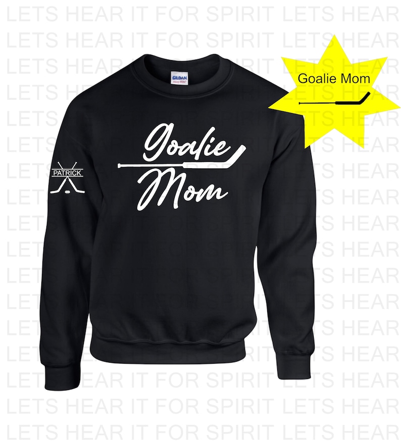K&ouml;nnte beinhalten: Schwarzer Pullover mit wei&szlig;em Text, der "Goalie Mom" lautet, und einer Grafik eines Hockeyschl&auml;gers. Der linke &Auml;rmel hat eine kleine wei&szlig;e Grafik von zwei gekreuzten Hockeyschl&auml;gern mit dem Wort "Patrick" dar&uuml;ber.