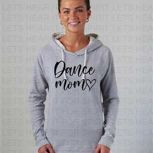 Puede incluir: Una sudadera con capucha gris con un gr&aacute;fico negro que dice "Dance Mom" con un coraz&oacute;n. La modelo lleva la sudadera y sonr&iacute;e.