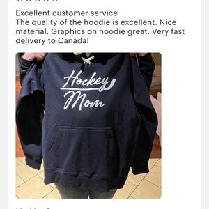 K&ouml;nnte beinhalten: Ein marineblauer Hoodie mit einem wei&szlig;en Aufdruck auf der Vorderseite, der "Hockey Mom" lautet. Der Hoodie hat eine Kapuze mit Kordelzug und eine K&auml;ngurutasche.