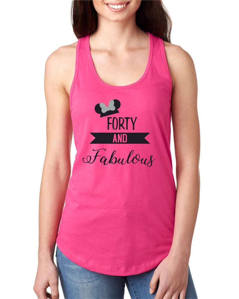 Pode incluir: Camisola de al&ccedil;as rosa com um gr&aacute;fico preto e branco que diz "Forty and Fabulous" com orelhas de Mickey Mouse de glitter prateado e um la&ccedil;o no topo.