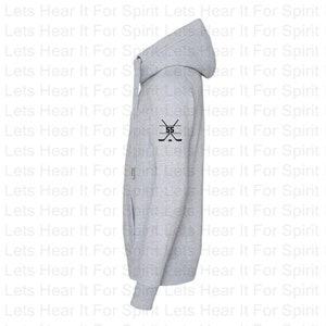 K&ouml;nnte beinhalten: Ein grauer Kapuzenpullover mit einem schwarzen Hockeyschl&auml;ger und der Nummer 55 auf dem linken &Auml;rmel.
