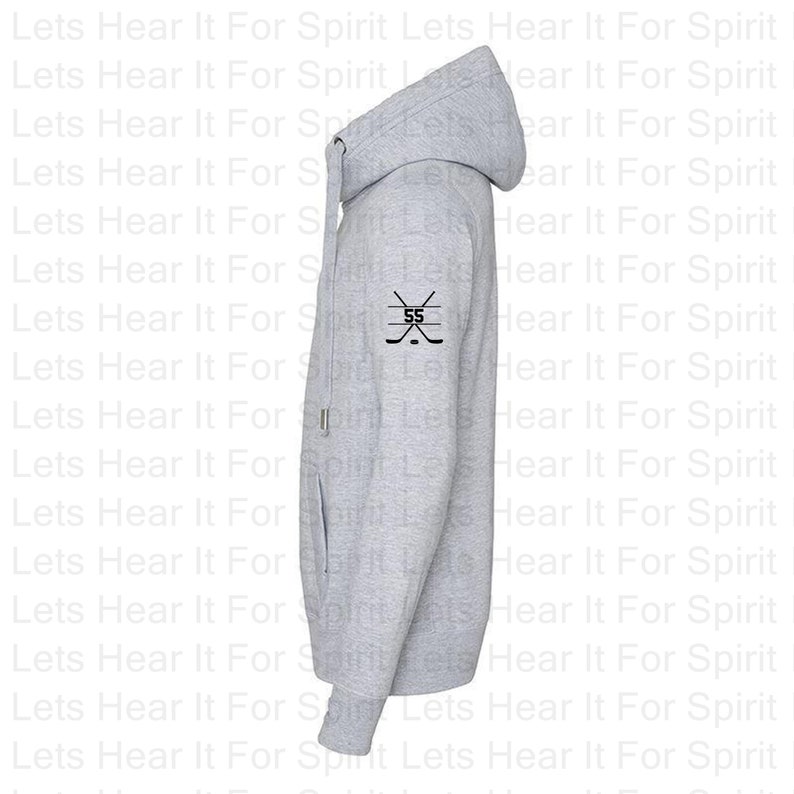 K&ouml;nnte beinhalten: Ein grauer Kapuzenpullover mit einem schwarzen Hockeyschl&auml;ger und der Nummer 55 auf dem linken &Auml;rmel.