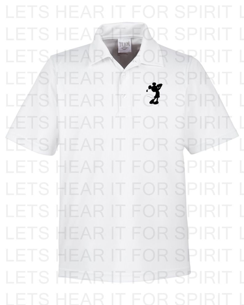 May include: White polo shirt with a black silhouette of Mickey Mouse playing golf on the left chest. The shirt has the text "TEAM" in a small black rectangle on the collar.