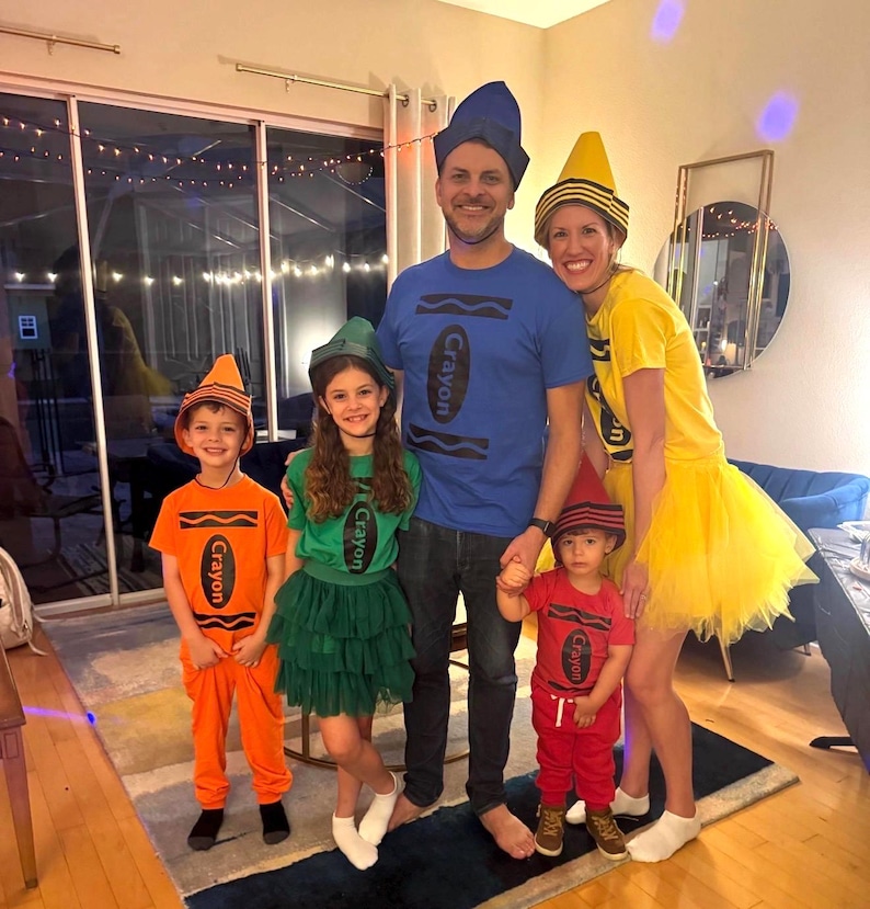 May include: A family of five wearing crayon-themed costumes. The group includes a blue crayon t-shirt, a yellow crayon t-shirt with a tulle skirt, a green crayon t-shirt with a tulle skirt, an orange crayon t-shirt with pants, and a red crayon t-shirt with pants.