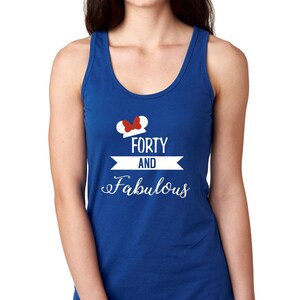 Pode incluir: Um top de al&ccedil;as azul royal com um gr&aacute;fico branco que diz "Forty and Fabulous" com um la&ccedil;o vermelho no topo de uma silhueta de orelha do Mickey Mouse branca.