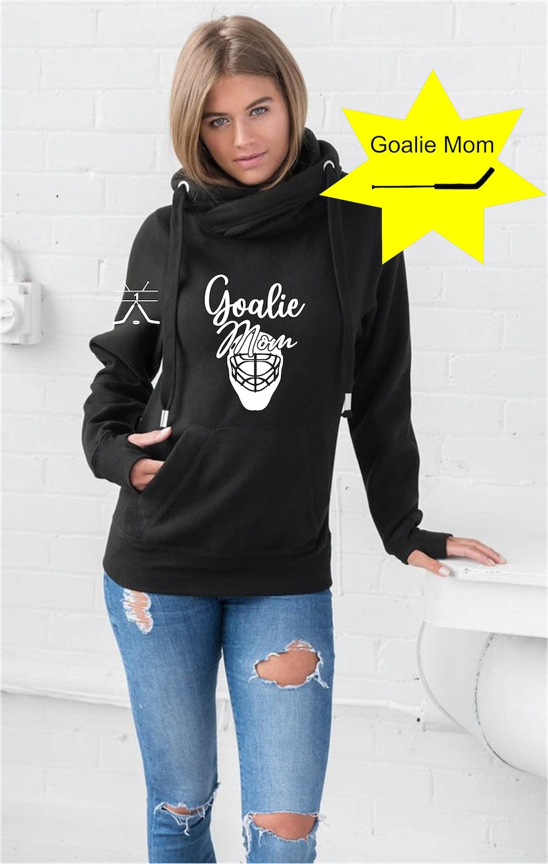 K&ouml;nnte beinhalten: Schwarzer Hoodie mit einem wei&szlig;en Aufdruck eines Hockeytorwart-Masken und dem Text "Goalie Mom". Der Hoodie hat einen Kapuzenkragen und eine Tasche auf der Vorderseite.