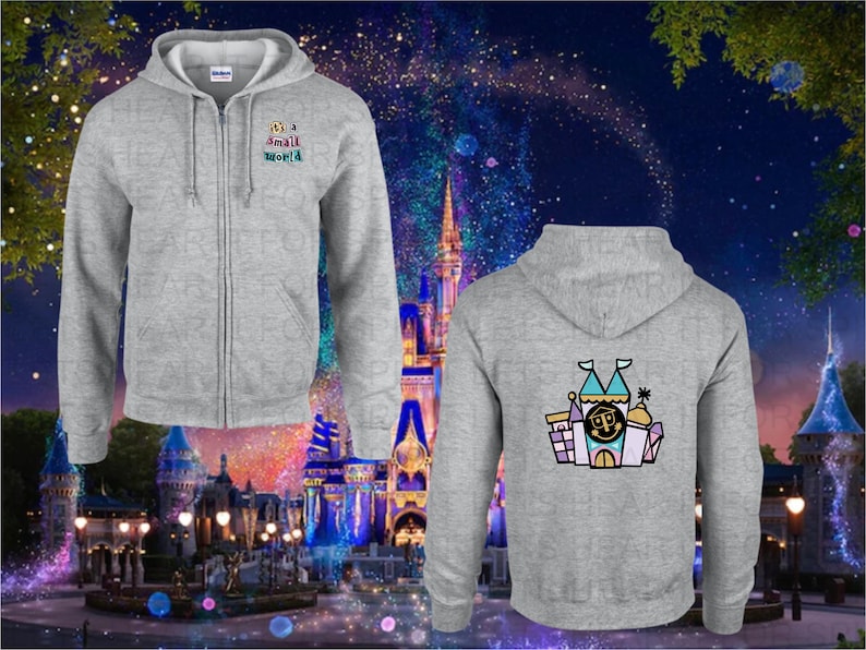 May include: A grey zip-up hoodie with a small world graphic on the front and a cartoon illustration of a castle on the back. The hoodie is in front of a blurred background of a nighttime amusement park.