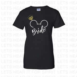 May include: Black t-shirt featuring a white Mickey Mouse head design with a gold glitter diamond above it. The text "Bride" is written in white below the Mickey Mouse head.