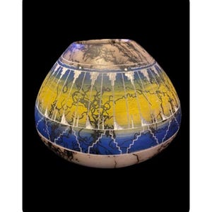 May include: A hand-painted ceramic pot with a yellow, blue and black geometric design. The pot is made by Native American artists and is a beautiful example of their craftsmanship.
