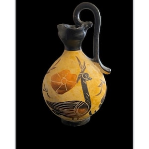 May include: A small, yellow ceramic jug with a black handle and a black and orange painted design of a bird and a flower.