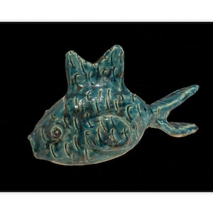 Könnte beinhalten: Eine tealblaue Keramik-Fischfigur mit einer strukturierten Oberfläche. Der Fisch hat einen großen, offenen Mund und eine Flosse auf dem Rücken.