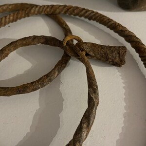 May include: Two rusty metal rings, one twisted and one smooth, connected by a rusty metal loop.