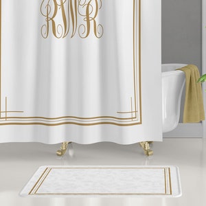 May include: White bath mat with a gold border. The mat has a soft, plush texture.