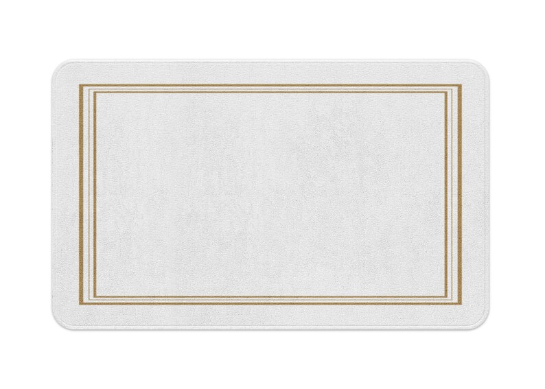 May include: A white bath mat with a double gold border.