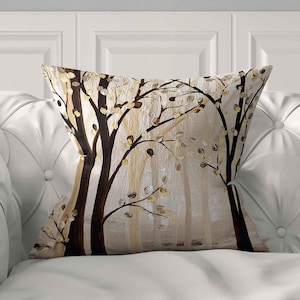 May include: A square throw pillow featuring a printed artistic design of dark brown tree trunks against a light beige background. The branches are adorned with small, scattered circular leaves in shades of gold, white, and dark brown, creating a forest scene.