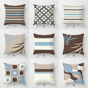May include: A collection of nine square throw pillows featuring various patterns in shades of brown, light blue, beige, and white. Designs include horizontal stripes, geometric circles, abstract leaf motifs, and square grid patterns, each numbered one through nine.