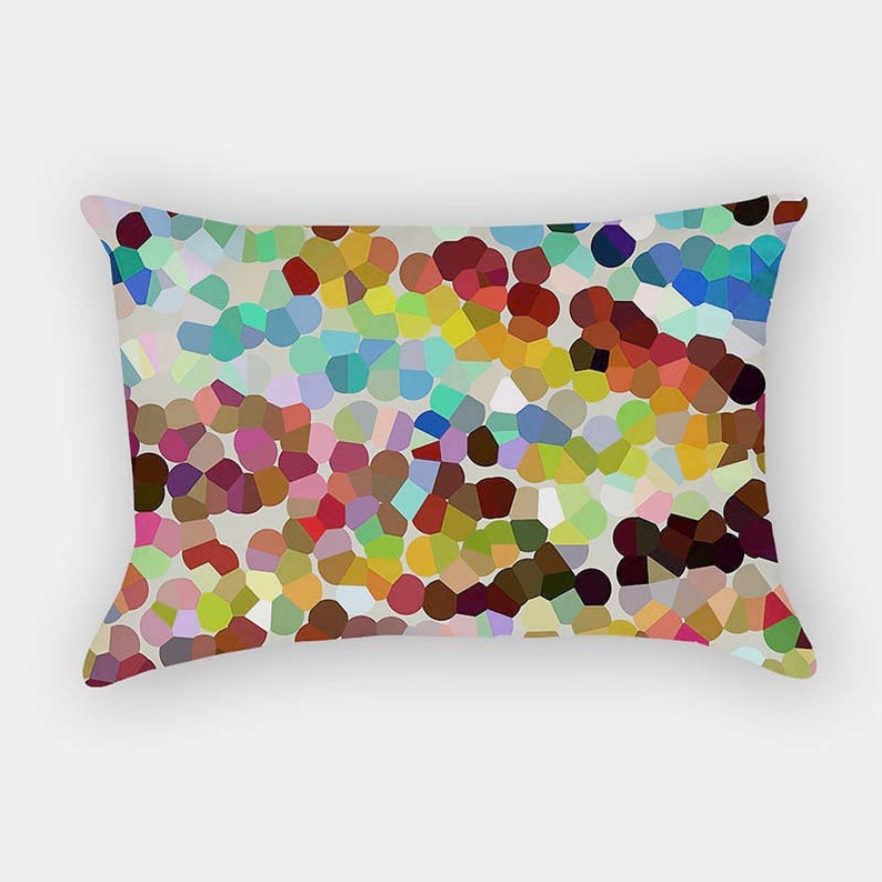 May include: A rectangular throw pillow featuring a vibrant, multi-colored mosaic pattern of irregular, rounded shapes. The design includes a diverse palette of red, blue, green, yellow, brown, and pink hues set against a light gray background.