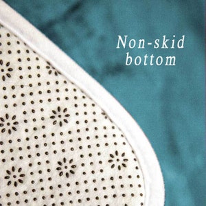 May include: Close-up of the non-skid bottom of a rug. The bottom is white with a pattern of small black dots and flower shapes.
