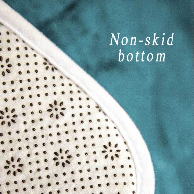 May include: Close-up of the non-skid bottom of a rug. The bottom is white with a pattern of small black dots and flower shapes.