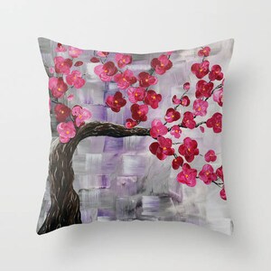 May include: A throw pillow with a painting of a pink cherry blossom tree on a purple and gray background.