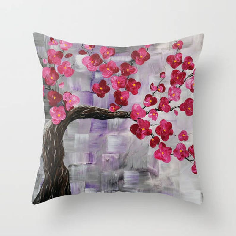 May include: A throw pillow with a painting of a pink cherry blossom tree on a purple and gray background.