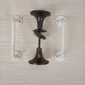 May include: Two white door handles with a black and brown door knob in the centre.