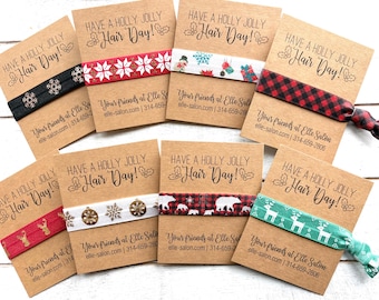 May include: Eight elastic hair ties on individual kraft paper cards. Each card features the text "HAVE A HOLLY JOLLY Hair Day!" and contact information for Elle Salon. The hair ties display various holiday patterns including snowflakes, reindeer, plaid, and polar bears.