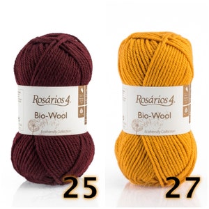 May include: Two skeins of Ros&aacute;rios 4 Bio-Wool yarn, one in deep burgundy and one in mustard yellow. Each skein features a white paper label with the brand name, product name, and a dandelion graphic. The numbers 25 and 27 are printed below.