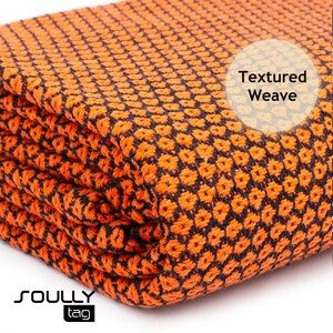 May include: Folded orange and black textured weave fabric. The fabric has a repeating pattern of small, raised squares. The words "Textured Weave" are in a white circle. The brand name "SOULLY" and the word "tag" are in the bottom left corner.