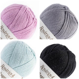 May include: Four round balls of yarn in light pink, grey, light blue, and black. Each ball features a white paper label with the text Ros&aacute;rios 4 printed in black. The yarn is wound in a smooth, consistent pattern, showing the texture of the fiber.