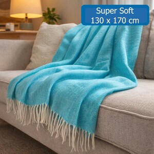 May include: A bright turquoise throw blanket with a herringbone pattern and white fringe along the bottom edge. The blanket features a soft texture and is labeled as Super Soft with dimensions of 130 x 170 cm printed on the fabric overlay.